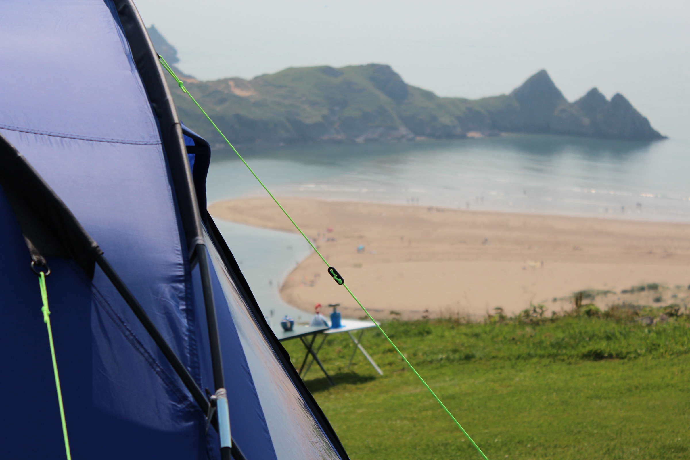 Looking out from a blue tent over the sands and three-peaked headland of Three Cliffs Bay, Gower